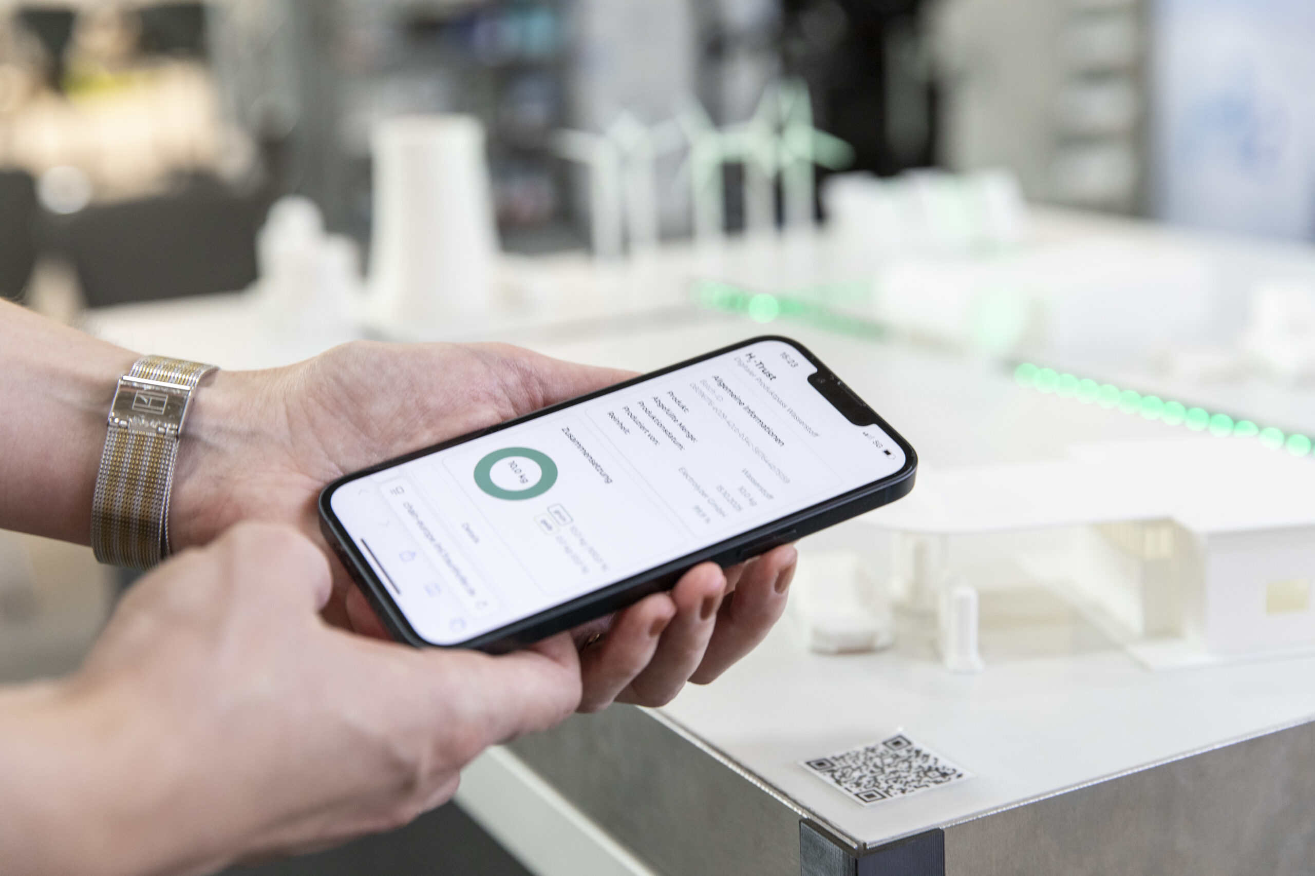 Frauenhände halten Smartphone mit Open Source Anwendung, digitaler Produktpass für Wasserstoff